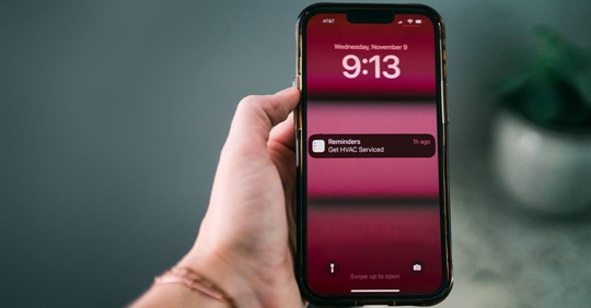 hand holding phone with HVAC reminder display on screen