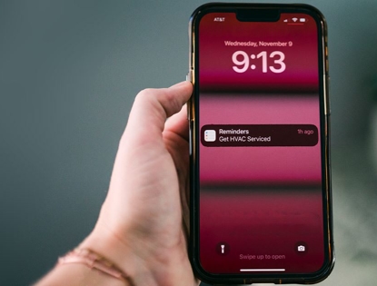 hand holding phone with HVAC reminder display on screen